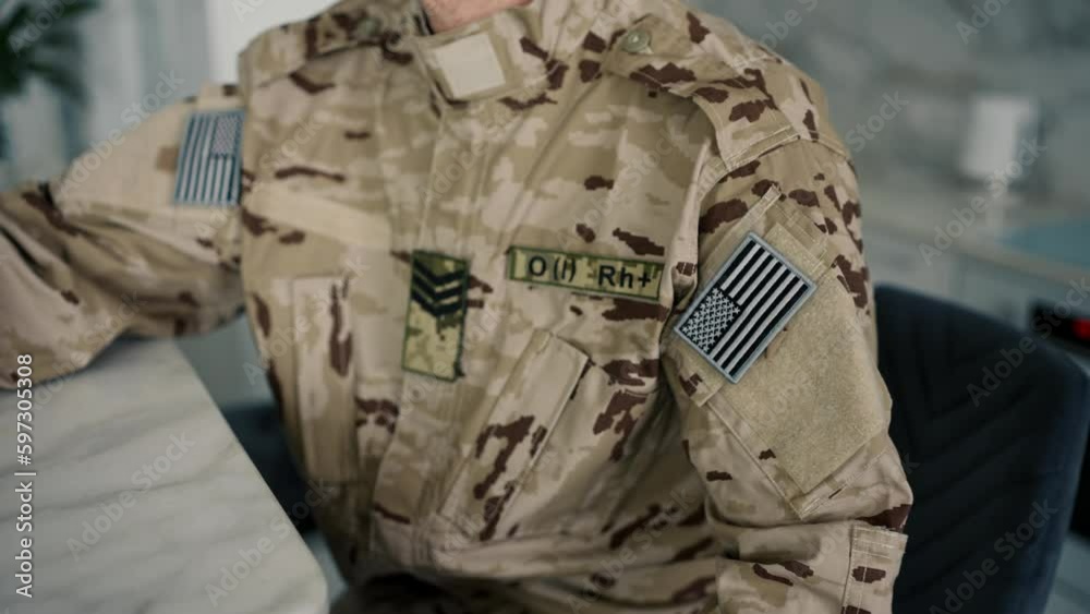 A soldier in camouflage sits at a table and turns his head to the camera. Camera movement back A soldier in camouflage sits at a table and turns his head to the camera. Camera movement back