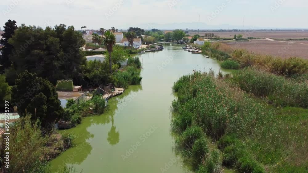 The flight of the drone along the river with small village. Boats moored at the pier. The flight of the drone along the river with small village. Boats moored at the pier.