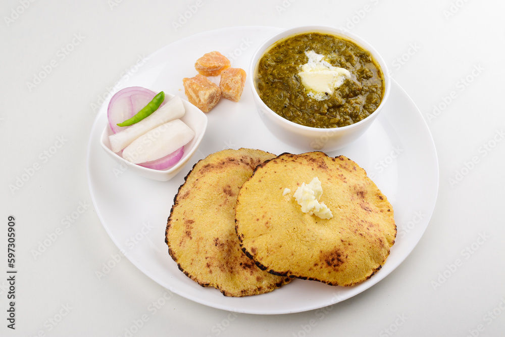 Sarson saag with corn chapati served with white makhan and jaggery in plate isolated on white background Sarson saag with corn chapati served with white makhan and jaggery in plate isolated on white background