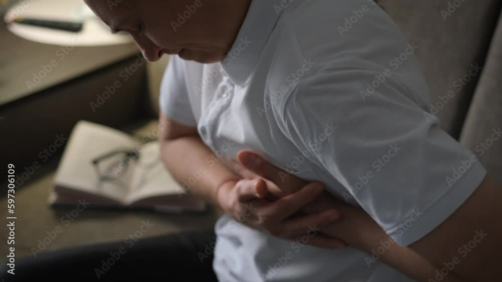 Adult woman clutching her heart with her hands during a heart attack