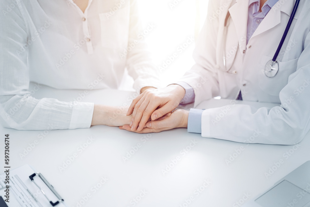 Doctor and patient sitting near each other at the table in clinic office. The focus is on female physician's hands reassuring woman, only hands, close up. Medicine concept Doctor and patient sitting near each other at the table in clinic office. The focus is on female physician's hands reassuring woman, only hands, close up. Medicine concept