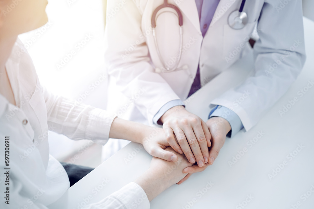 Doctor and patient sitting near each other at the table in clinic office. The focus is on female physician's hands reassuring woman, only hands, close up. Medicine concept Doctor and patient sitting near each other at the table in clinic office. The focus is on female physician's hands reassuring woman, only hands, close up. Medicine concept