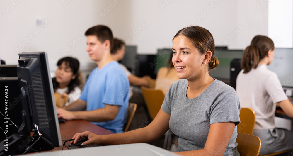 Smiling girl student looking at monitor while working in computer room in college
