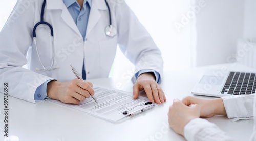 Doctor and patient discussing current health questions while sitting opposite of each other at the table in clinic, just hands closeup. Medicine concept