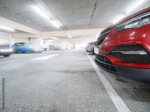 Row of cars in a car park or dealership. Selective focus. Red color car in foreground. Busy parking lot of a shopping mall. Parking prices and vehicle density in town issue. Soft cinematic look