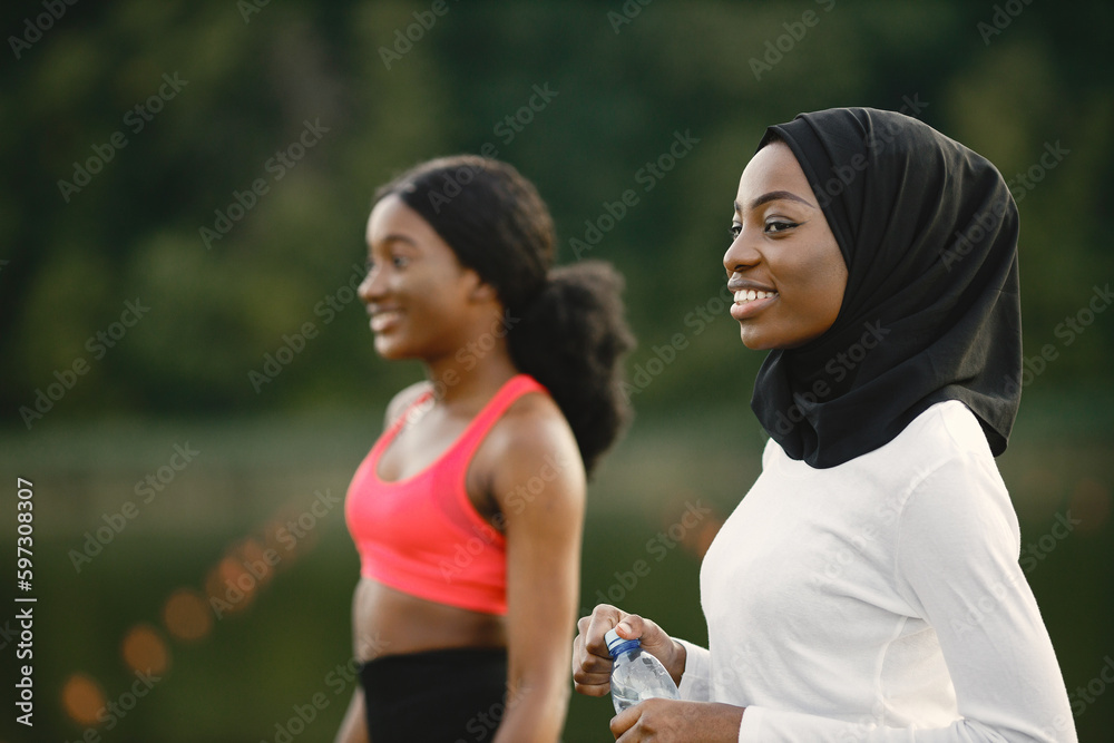 Two muslim women holding a bottles with water while doing workout Two muslim women holding a bottles with water while doing workout