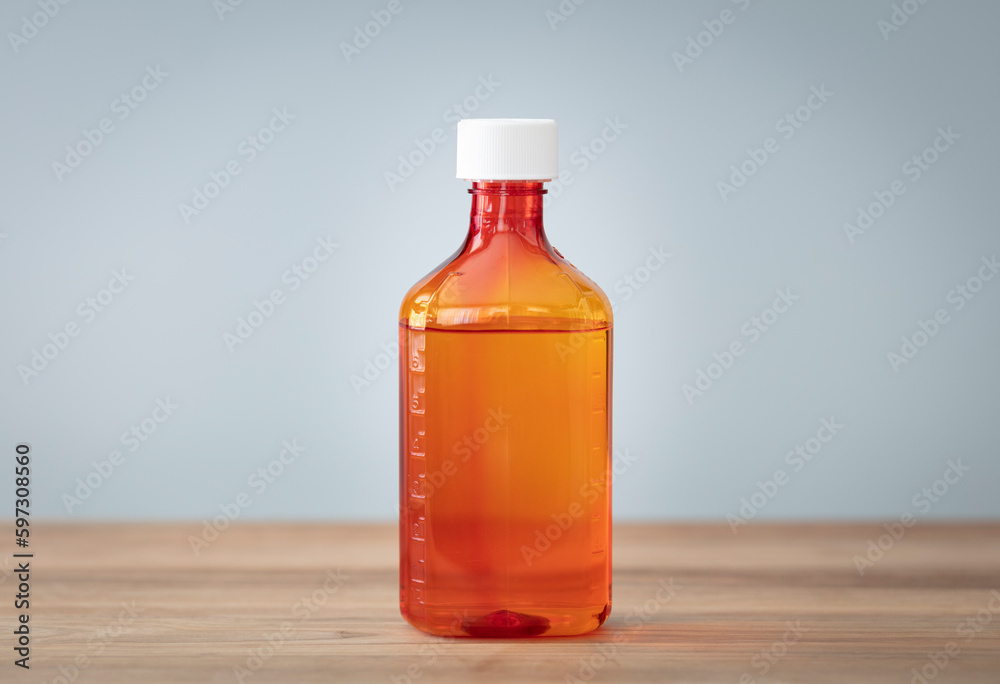 Bottle with liquid medicine. Transparent orange vial with lid on neutral background. Stop your cold today. Copy space for text or image. Bottle with liquid medicine. Transparent orange vial with lid on neutral background. Stop your cold today. Copy space for text or image.