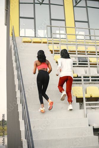 Two black women running up a stairs on a stadium
