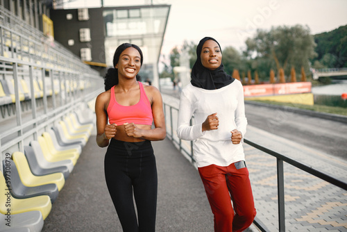 Two black women running on a stadium