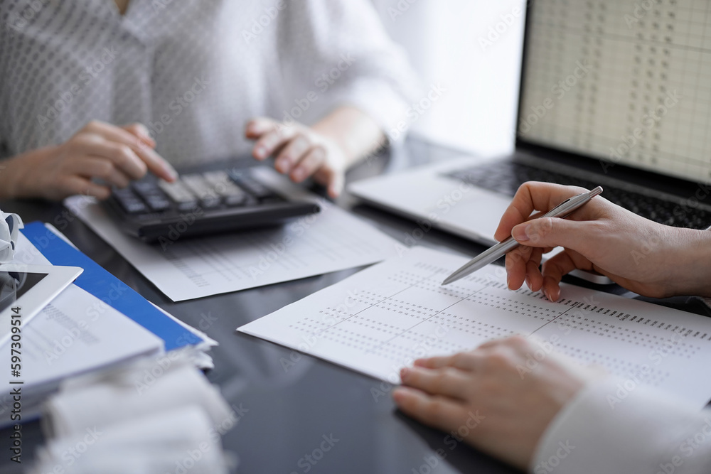 Fototapeta premium Woman accountant using a calculator and laptop computer while counting taxes for a client. Business audit concepts