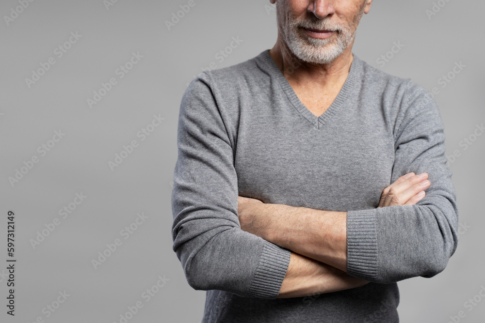 Cropped portrait gray haired bearded mature man posing with arms crossed on grey isolated background. Cropped portrait gray haired bearded mature man posing with arms crossed on grey isolated background.