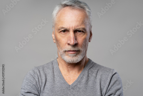 Headshot of confident successful serious senior man 60 years old, retired pensioner isolated on grey © Maria Vitkovska