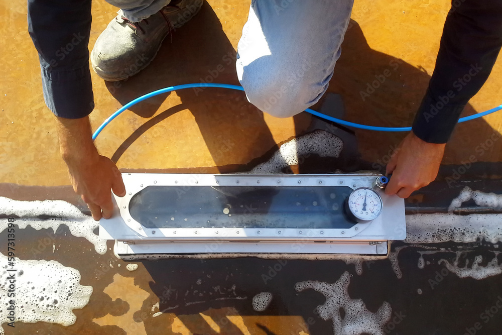 Inspector performs leak test on welds of storage tank with vacuum box