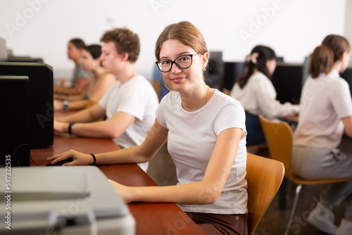 Smiling female student in glasses using PC and studying computer science in the classroom © JackF