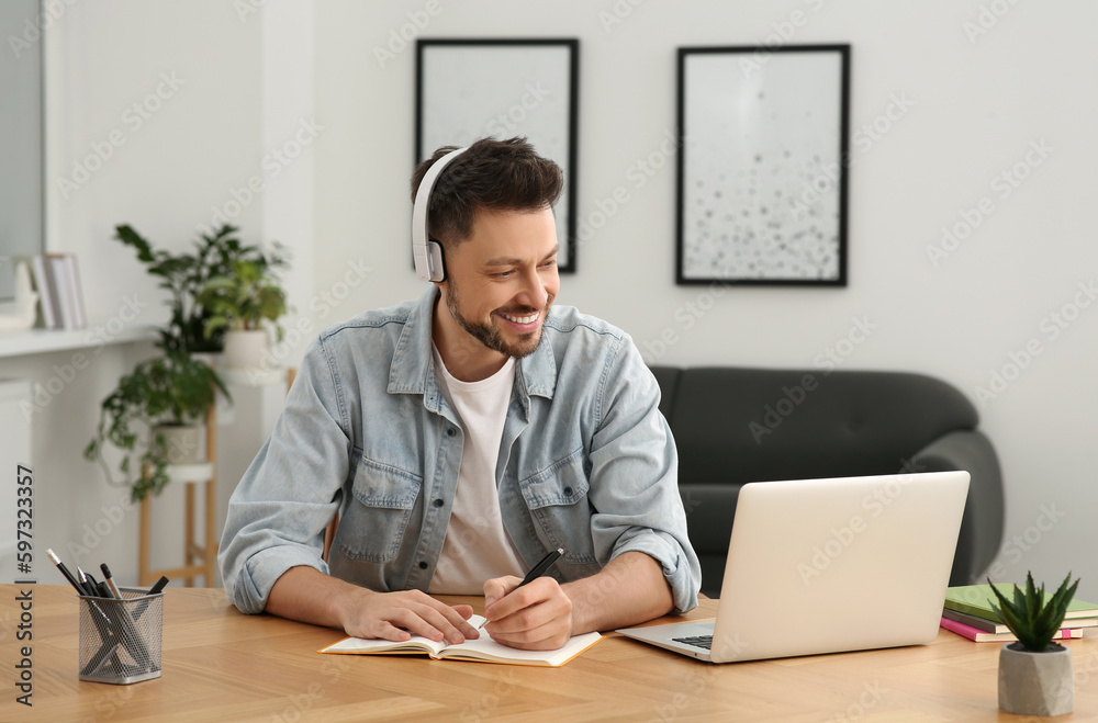 Man in headphones studying on laptop at home. Online translation course Man in headphones studying on laptop at home. Online translation course