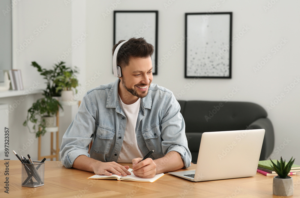 Man in headphones studying on laptop at home. Online translation course