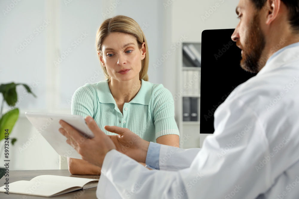 Fototapeta premium Doctor consulting patient at wooden table in clinic
