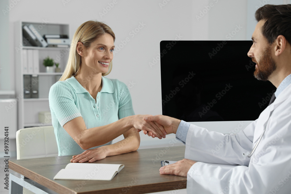 Fototapeta premium Doctor shaking hands with happy patient in hospital