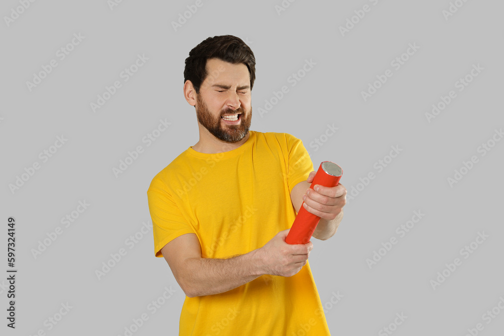 Emotional man with party popper on light grey background Emotional man with party popper on light grey background