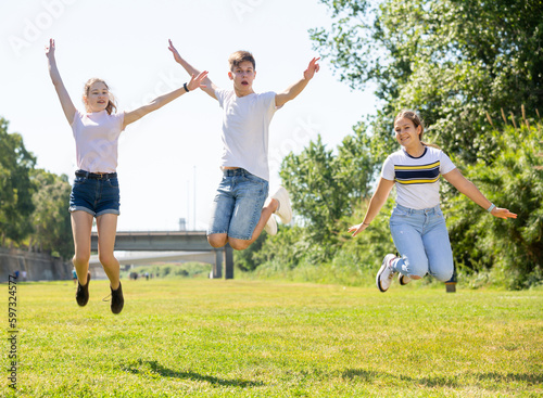 Happy teenagers jumping on the green lawn on spring