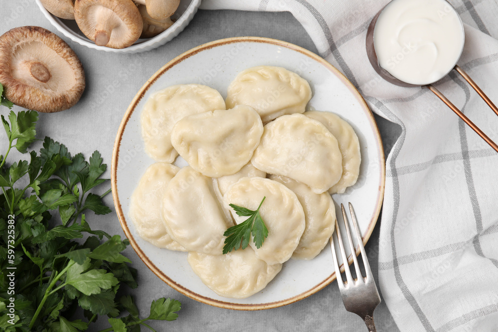 Delicious dumplings (varenyky) with mushrooms and parsley served on light grey table, flat lay