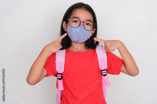 Asian kid student pointing to medical mask that she wear photo