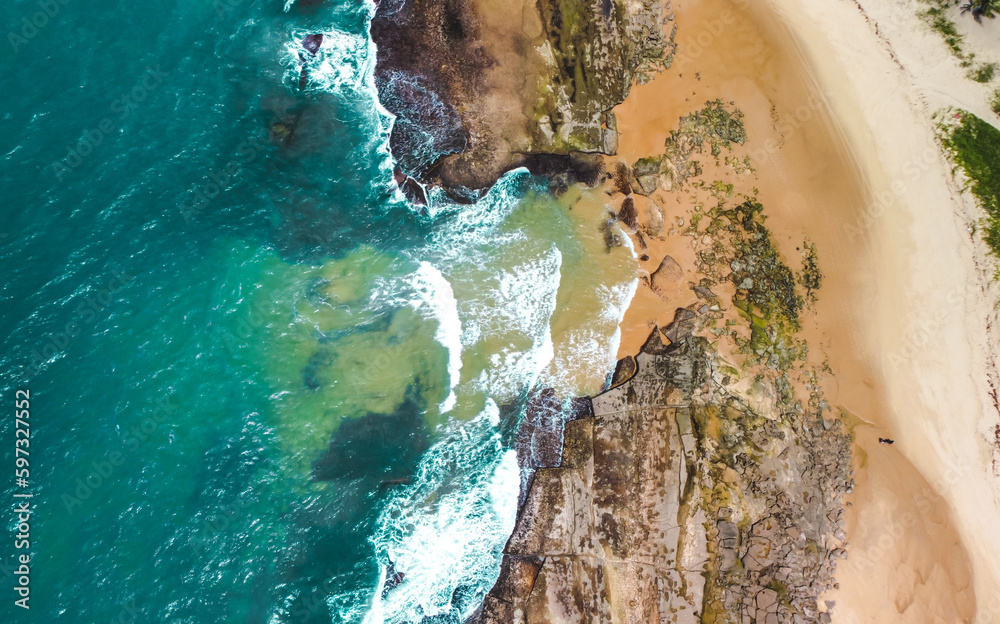 view of a tropical island on paradisiacal beach. blue sea with waves and stones.