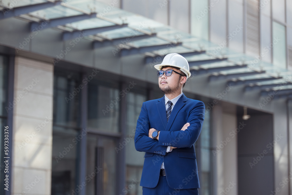 Handsome engineer wearing suit and hard hat or white helmet on building background. Engineer using tablet for checking construction about modern building. copy space for text. Handsome engineer wearing suit and hard hat or white helmet on building background. Engineer using tablet for checking construction about modern building. copy space for text.