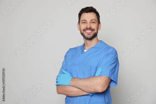 Doctor or medical assistant (male nurse) in uniform on light grey background. Space for text