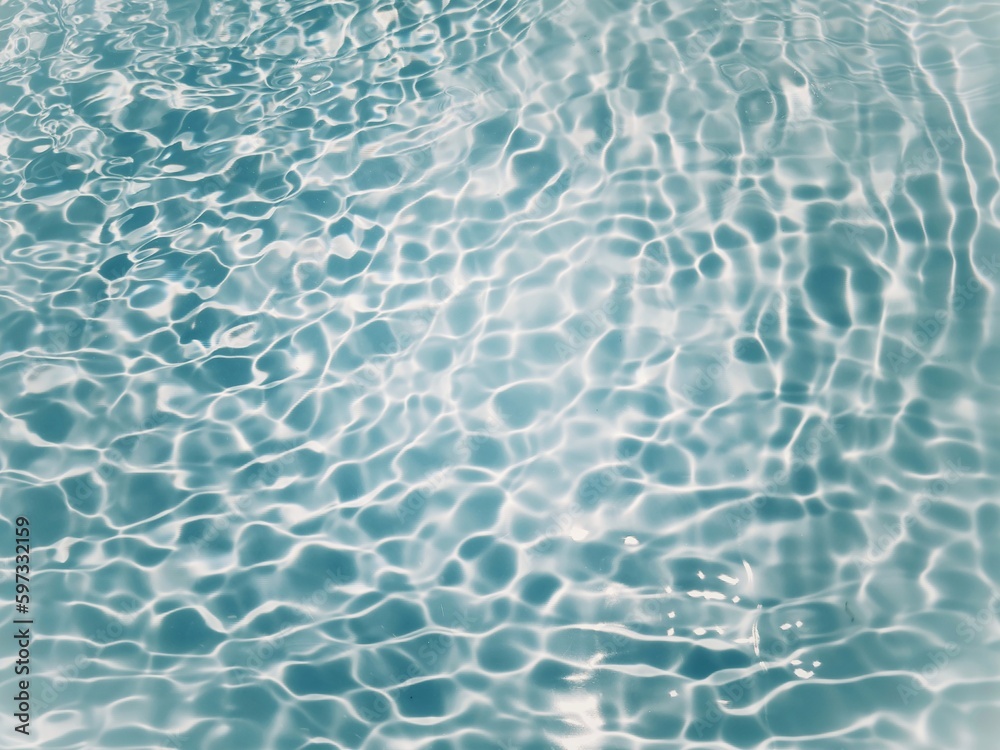Obraz premium Blue water with ripples on the surface. Defocus blurred transparent blue colored clear calm water surface texture with splashes and bubbles. Water waves with shining pattern texture background.