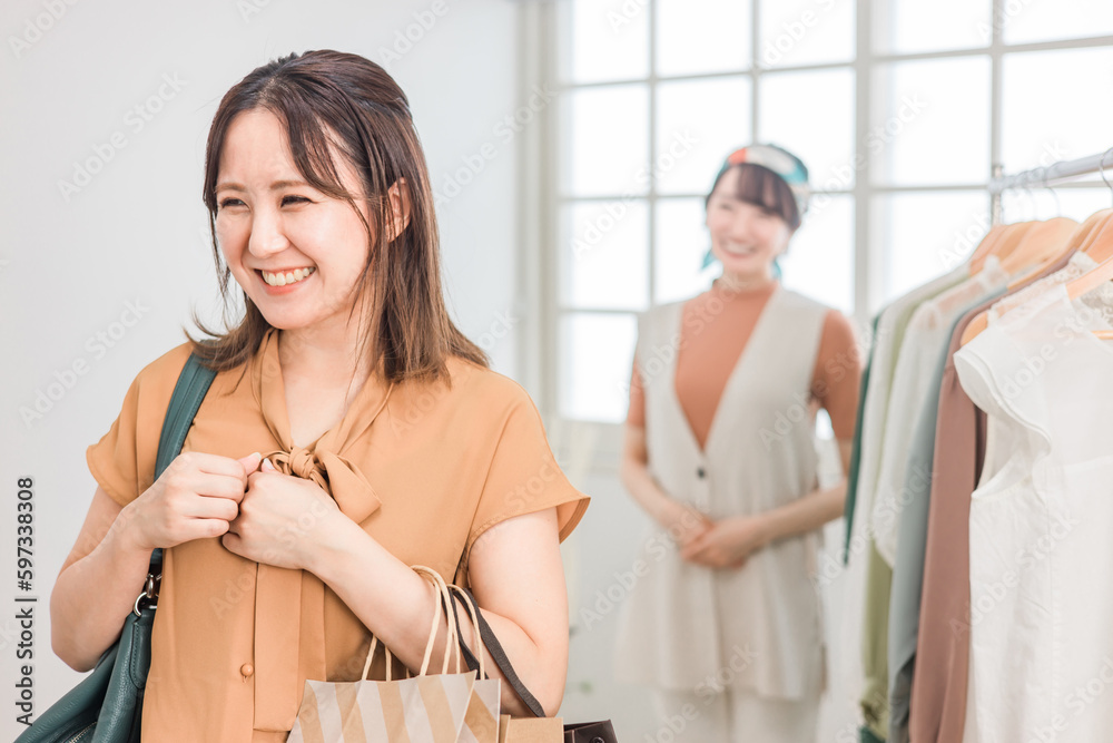 洋服屋・アパレルショップで買い物をする女性とショップ店員
