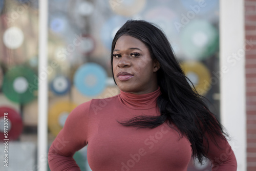 Wearing a sleek, long-sleeved turtleneck, a model expresses a colorful, confident pose. As a Black woman of trans experience, she affirms her freedom to be her authentic self.