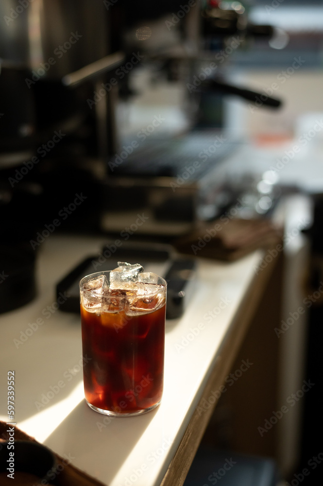 A cup of iced coffee with a clear plastic cup sits on a table in a cafe
