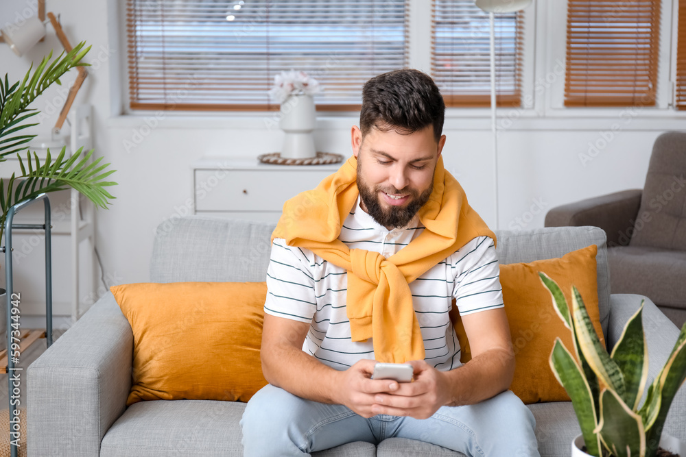 Young bearded man using mobile phone at home