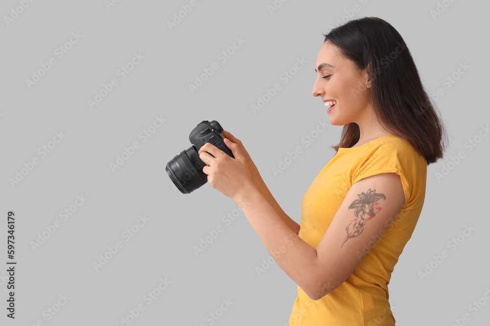 Obraz premium Female photographer with professional camera on grey background