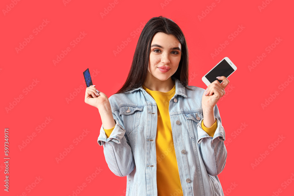 Pretty young woman with mobile phone and credit card on red background Pretty young woman with mobile phone and credit card on red background