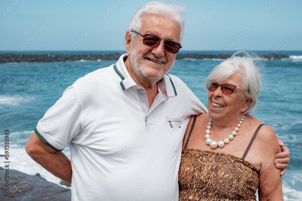 Tender senior couple hugging standing near beach enjoying beach vacation and freedom. Retirement lifestyle concept