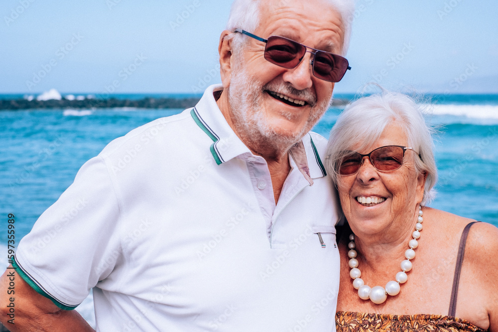Portrait of happy senior couple hugging standing near beach enjoying beach vacation and freedom. Retirement lifestyle concept