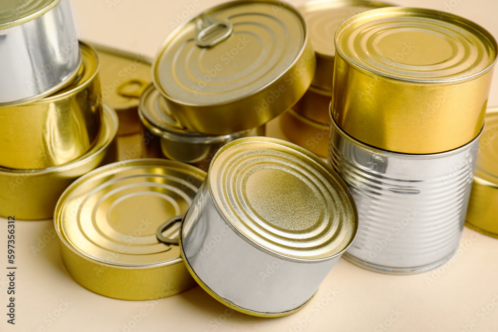 Different tin cans with fish on beige background, closeup Different tin cans with fish on beige background, closeup