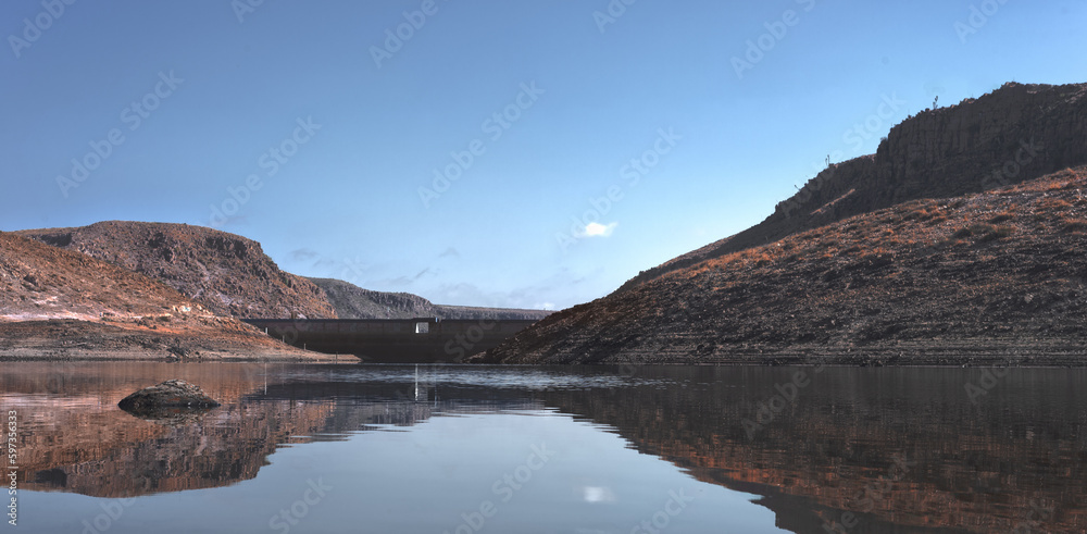 lake view of a dam among the plain of an arid climate with blue sky and few clouds, without people and animals, place of mountain hike