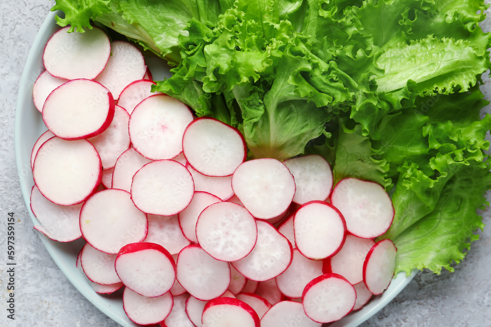 Plate with fresh slices of radish and lettuce on grey grunge background Plate with fresh slices of radish and lettuce on grey grunge background