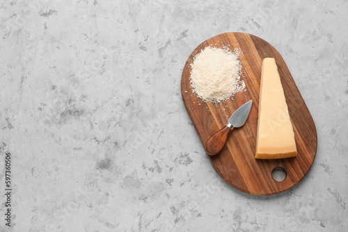 Wooden board with tasty Parmesan cheese on grunge background