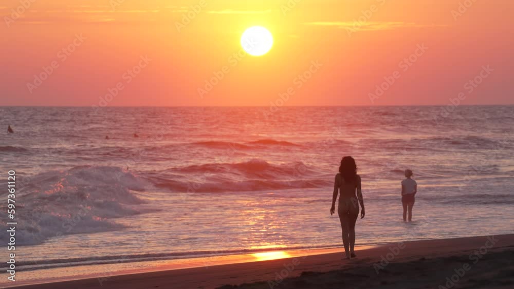 Silhouettes of People and Woman Walking on Sandy Beach Toward Ocean and Waves on Idyllic Sunset, Slow Motion Silhouettes of People and Woman Walking on Sandy Beach Toward Ocean and Waves on Idyllic Sunset, Slow Motion