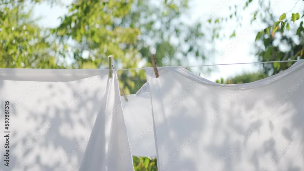 White sheets held up with clothes pegs on a washing line outside
