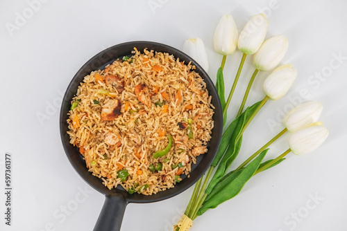 Chicken Fried Rice in black serve bowl isolated on white background. Szechuan Rice is indo-chinese cuisine dish with bell peppers, green beans, carrot, chicken breasts. Top view.