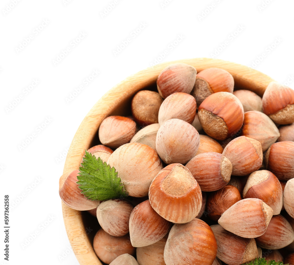 Bowl with shelled hazelnuts on white background