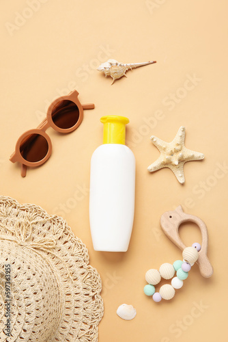 Sunscreen cream for baby with beach accessories on beige background