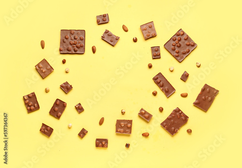Frame made of tasty chocolate with nuts on yellow background