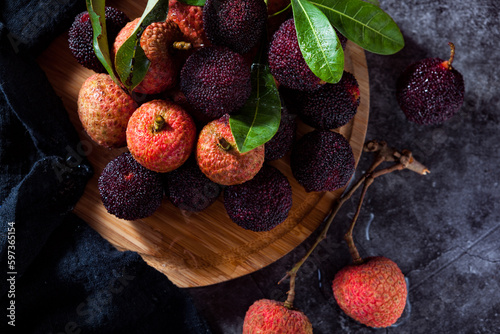 red bayberry(waxberry) and lychee placed together on marble tabletop, dark indoor background photo