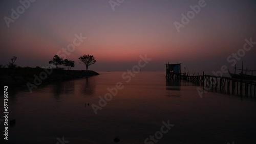 Blurred nature background of the morning sun by the sea, a beautiful golden light, among the trees, rocks and local fishing boats, the beauty of nature during the day. photo